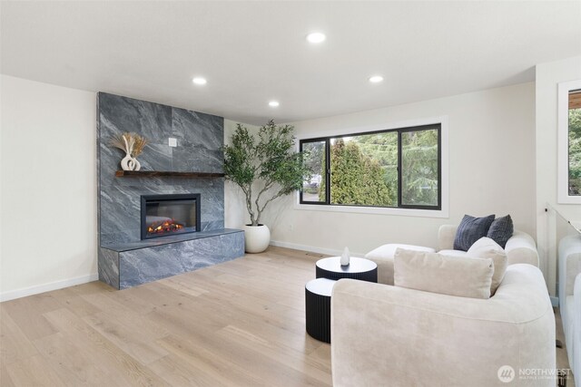 living room featuring recessed lighting, wood finished floors, a high end fireplace, and a healthy amount of sunlight