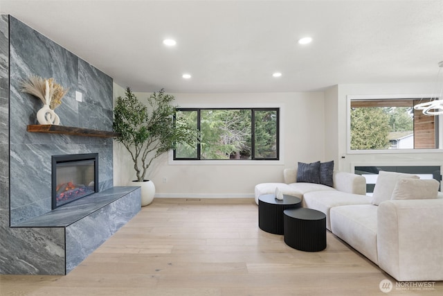 living area featuring a tile fireplace, baseboards, recessed lighting, and wood finished floors