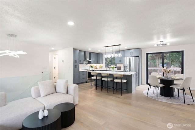 living area with light wood-style floors, a chandelier, a textured ceiling, and recessed lighting