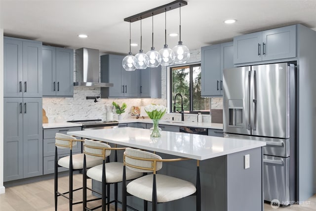 kitchen with a kitchen breakfast bar, wall chimney exhaust hood, light countertops, and stainless steel fridge with ice dispenser