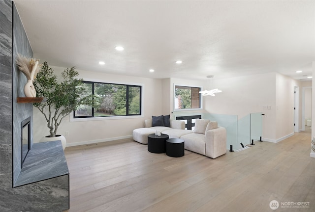 living area featuring recessed lighting, a large fireplace, an upstairs landing, baseboards, and light wood-type flooring