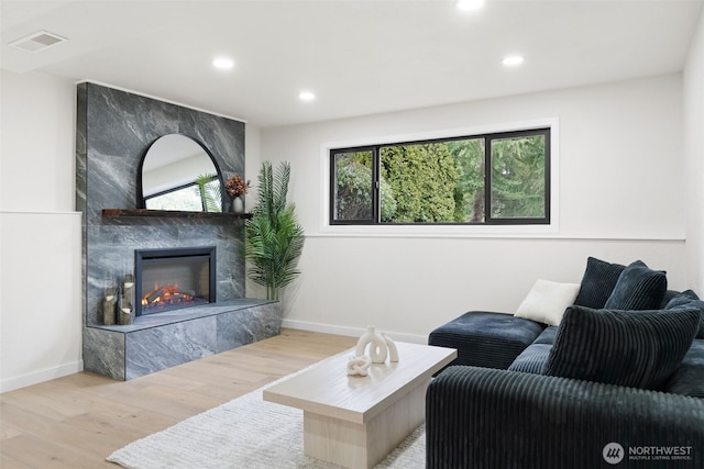 living room featuring recessed lighting, a fireplace, wood finished floors, visible vents, and baseboards