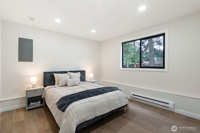 bedroom featuring recessed lighting, wood finished floors, baseboards, baseboard heating, and electric panel