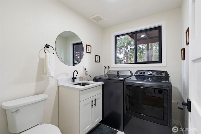 laundry room featuring laundry area, visible vents, a sink, and washing machine and clothes dryer