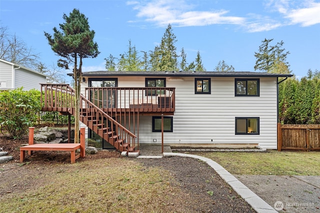 rear view of house with stairs, fence, a lawn, and a wooden deck