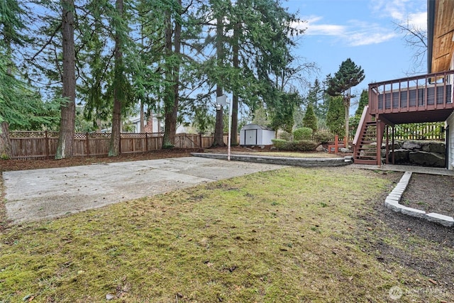 view of yard featuring a fenced backyard, an outdoor structure, stairway, a wooden deck, and a shed