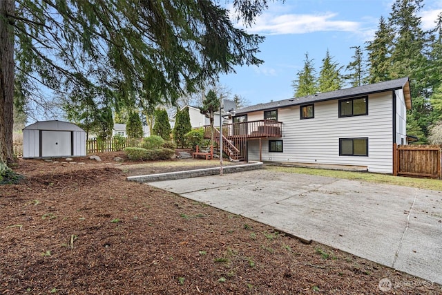 rear view of property with a storage shed, fence, a deck, an outdoor structure, and a patio area