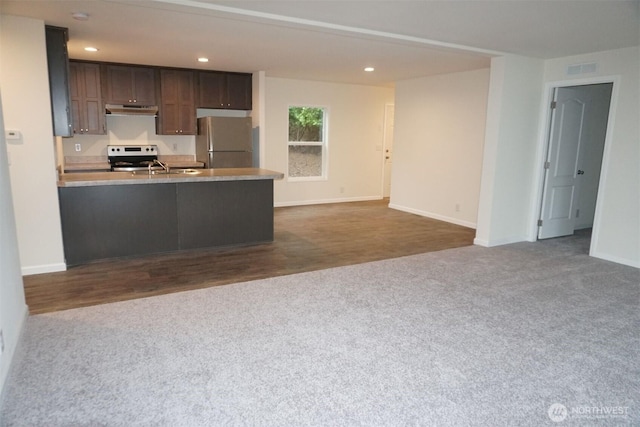 kitchen with recessed lighting, dark colored carpet, appliances with stainless steel finishes, a peninsula, and under cabinet range hood