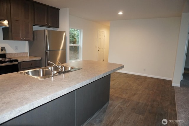 kitchen featuring stainless steel appliances, dark wood-style flooring, a sink, baseboards, and light countertops