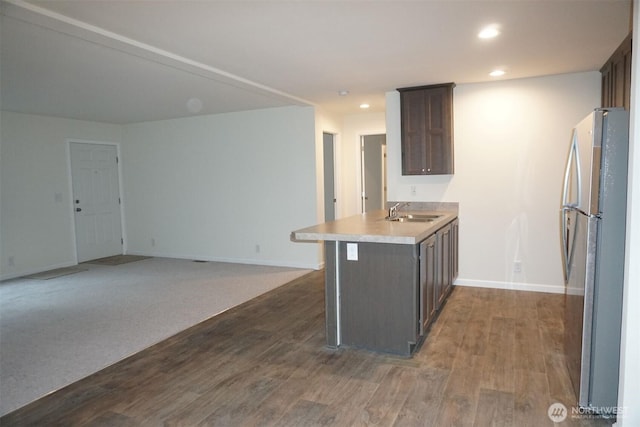 kitchen with dark wood-style flooring, freestanding refrigerator, a peninsula, a sink, and recessed lighting