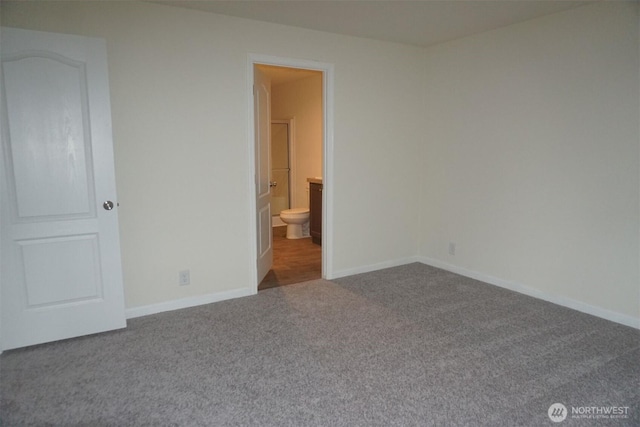 unfurnished bedroom featuring ensuite bathroom, carpet floors, and baseboards