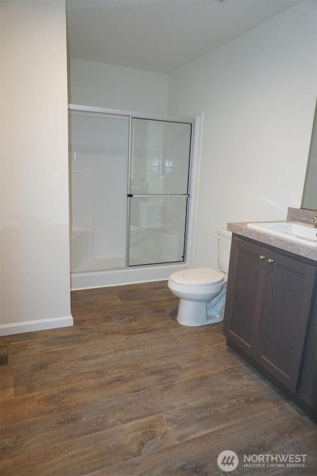 full bathroom with a shower with door, vanity, toilet, and wood finished floors