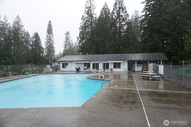 community pool with a patio area and fence