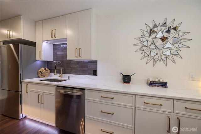 kitchen with dark wood finished floors, decorative backsplash, appliances with stainless steel finishes, white cabinetry, and a sink