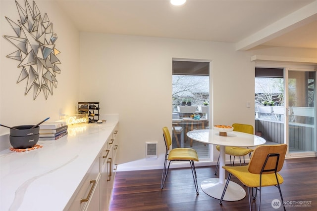 dining space featuring dark wood-style floors, visible vents, and baseboards