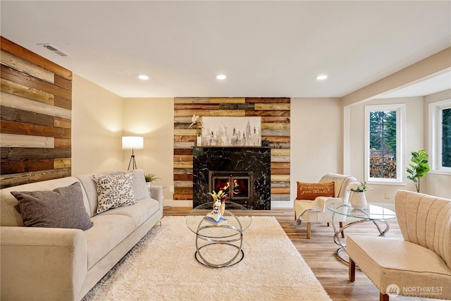 living area with wooden walls, recessed lighting, a fireplace, wood finished floors, and visible vents