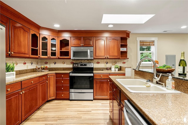 kitchen featuring a sink, appliances with stainless steel finishes, backsplash, open shelves, and light wood finished floors