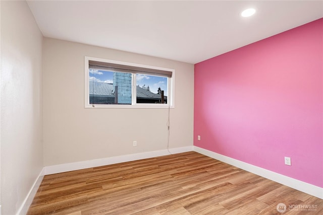 empty room with baseboards, wood finished floors, and recessed lighting