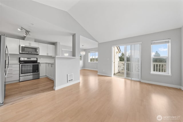 kitchen with stainless steel appliances, lofted ceiling, visible vents, open floor plan, and light wood-type flooring