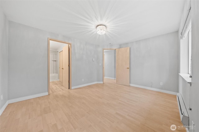 unfurnished bedroom featuring a baseboard heating unit, light wood-type flooring, baseboards, and ensuite bathroom