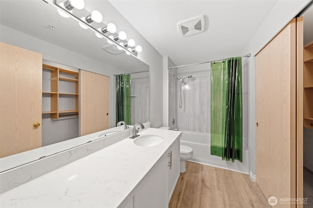 full bath featuring toilet, wood finished floors, visible vents, vanity, and shower / bath combo