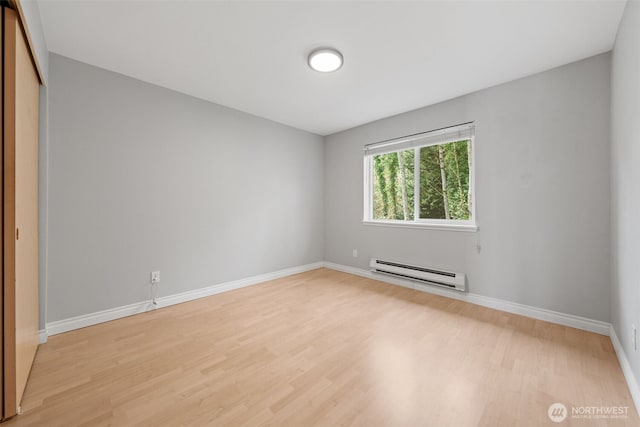 unfurnished room featuring light wood-style flooring, baseboards, and baseboard heating