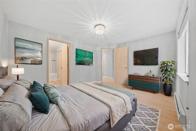 bedroom featuring light wood-style floors, baseboards, a baseboard heating unit, and ensuite bathroom