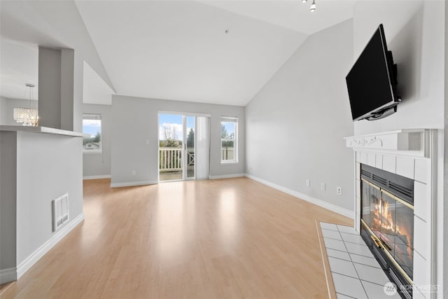 unfurnished living room with lofted ceiling, light wood-style flooring, a fireplace, and visible vents