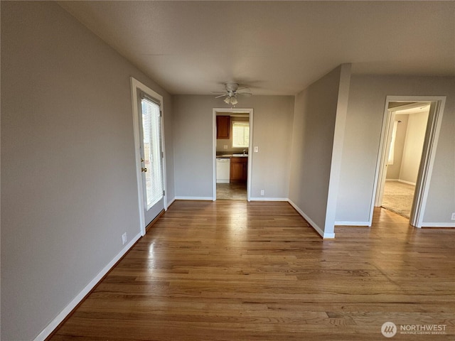 unfurnished room with a ceiling fan, baseboards, and wood finished floors