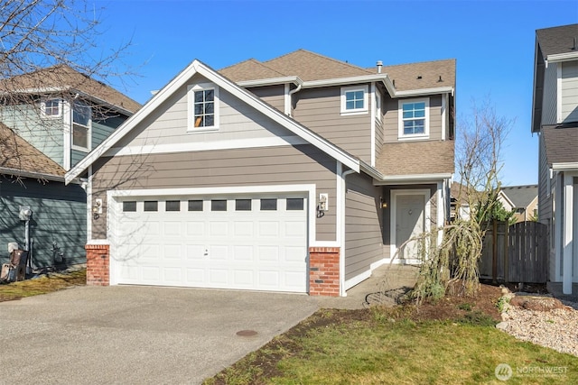 craftsman-style home with a garage, brick siding, fence, driveway, and roof with shingles