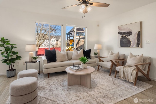 living area with baseboards, a ceiling fan, and wood finished floors