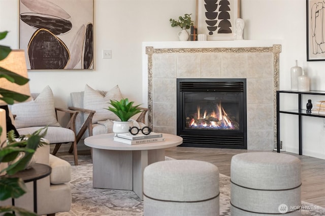 sitting room with a tiled fireplace and wood finished floors