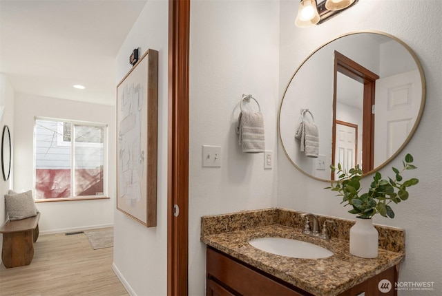 bathroom featuring visible vents, baseboards, wood finished floors, and vanity