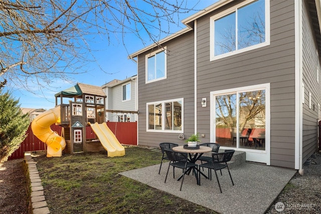 rear view of property with fence, a playground, and a patio