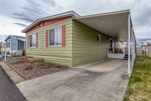 view of side of property with an attached carport, driveway, and an outbuilding