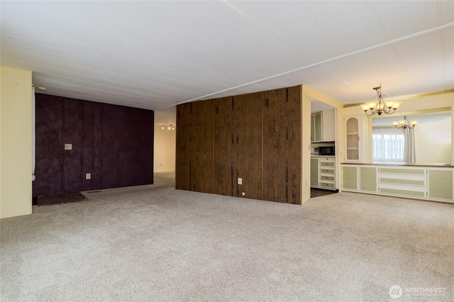 carpeted spare room with wooden walls and a notable chandelier