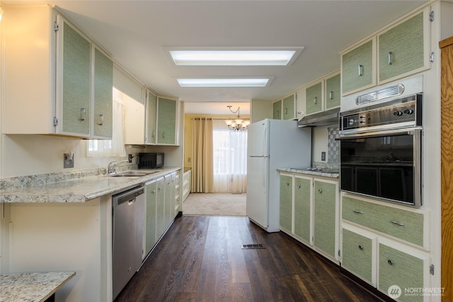 kitchen with dark wood-style floors, a sink, a chandelier, under cabinet range hood, and black appliances