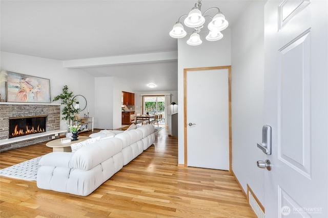 living area with light wood-type flooring, vaulted ceiling with beams, a fireplace, and visible vents