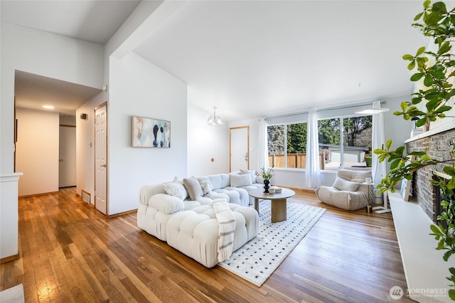 living area featuring lofted ceiling, a stone fireplace, and wood finished floors