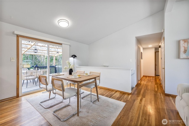 dining area featuring light wood-type flooring and lofted ceiling