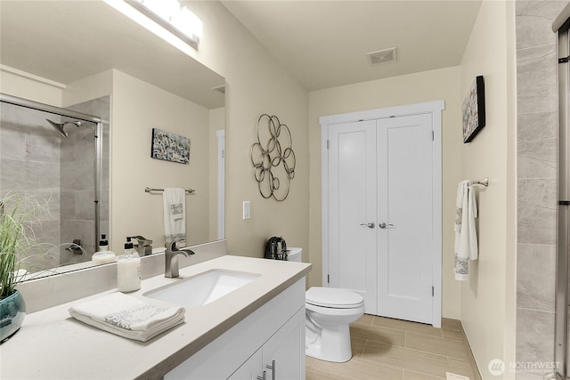 bathroom featuring visible vents, a tile shower, vanity, and toilet