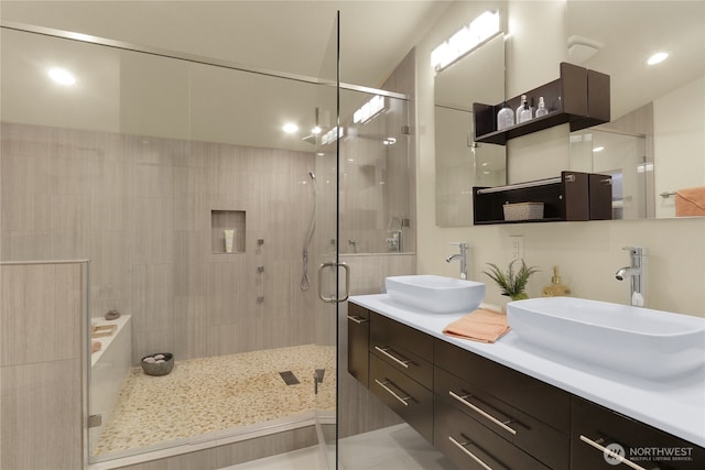 bathroom featuring double vanity, a shower stall, and a sink