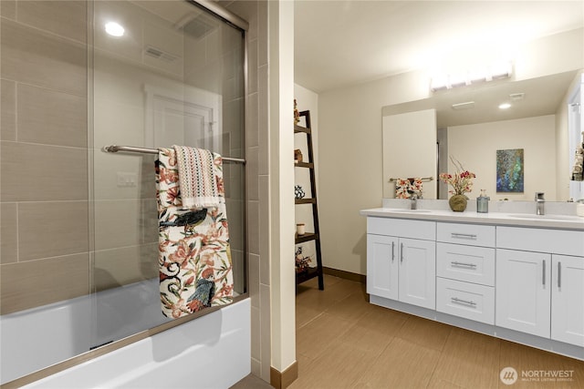 bathroom with combined bath / shower with glass door, vanity, and baseboards