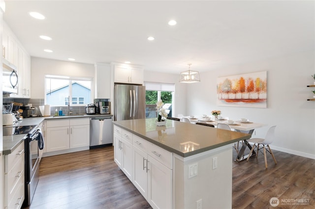 kitchen with a center island, dark wood-style flooring, hanging light fixtures, appliances with stainless steel finishes, and white cabinets