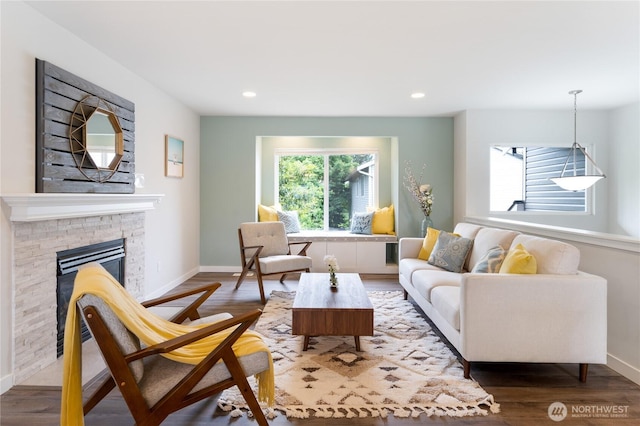 living area with a stone fireplace, baseboards, and wood finished floors