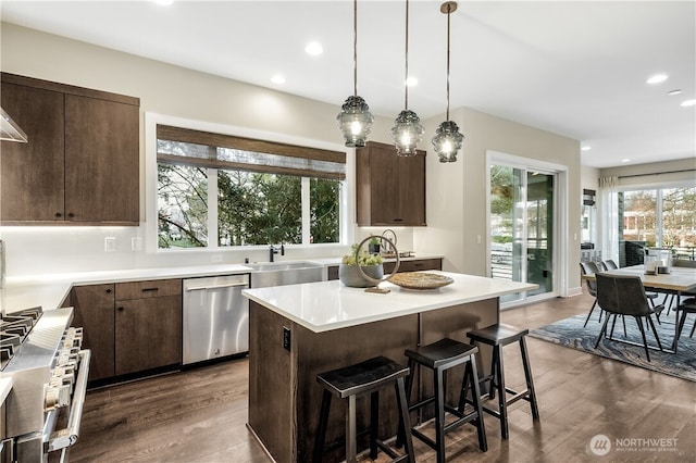 kitchen with dark wood finished floors, light countertops, appliances with stainless steel finishes, a sink, and dark brown cabinetry