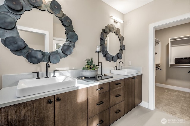 full bathroom with double vanity, a sink, and baseboards