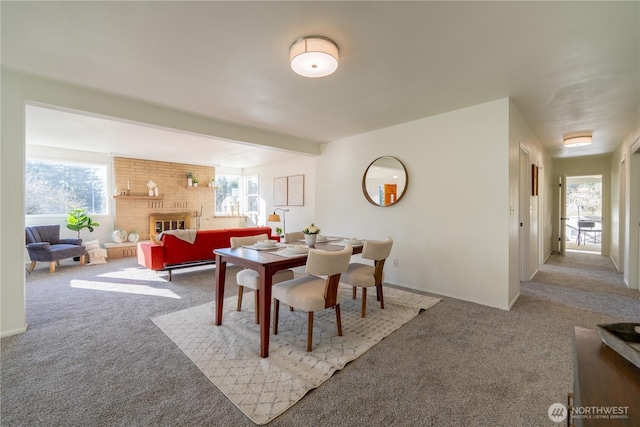 dining area with carpet floors, a fireplace, and beamed ceiling