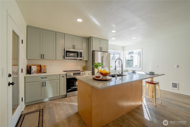 kitchen with light wood-style flooring, stainless steel appliances, a sink, and gray cabinetry