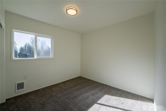 empty room with visible vents and dark colored carpet